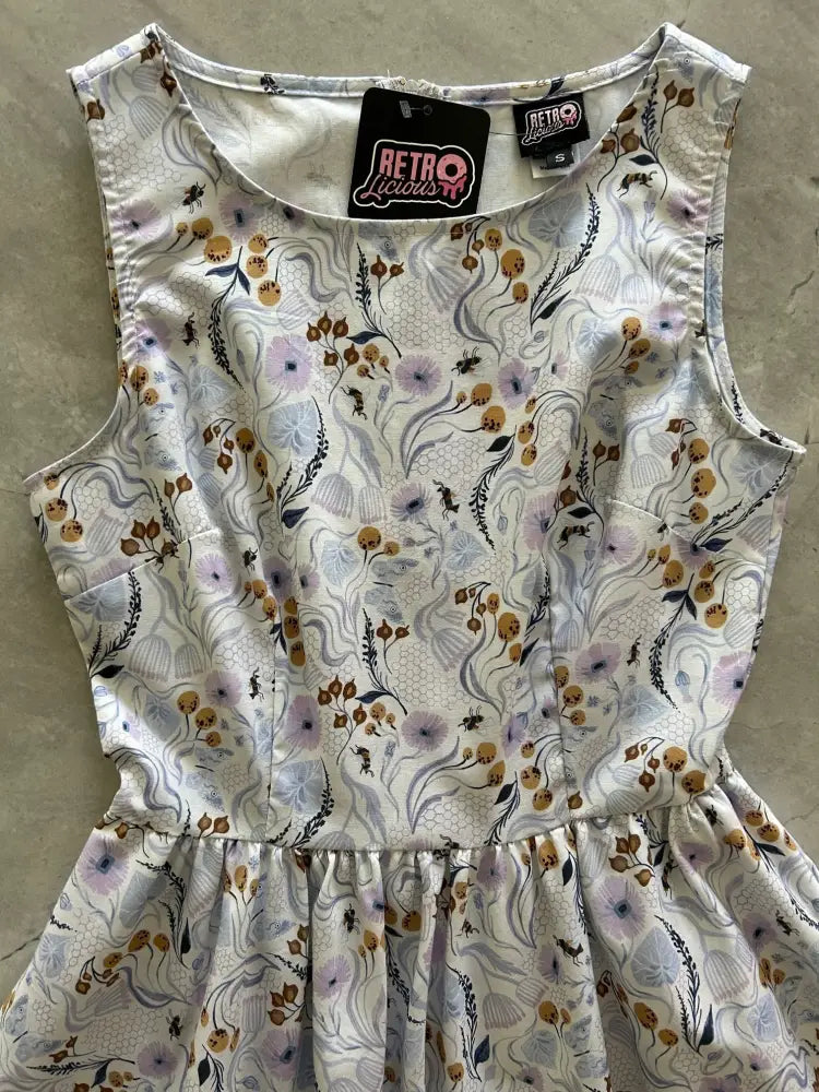 A sleeveless white cotton Pollinators vintage blue floral A-line dress with purple brown and black blossoms and pockets