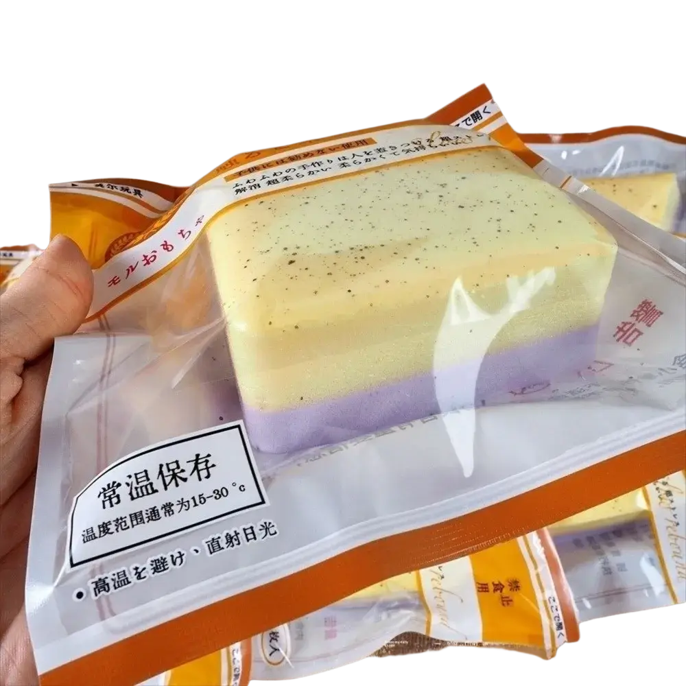 A layered pastel-colored mochi dessert in clear packaging with orange and white branding next to a polyester acrylic winter scarf