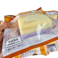 A rectangular layered soap bar with pale yellow and purple layers packaged in clear plastic with orange and white labeling containing polyester acrylic