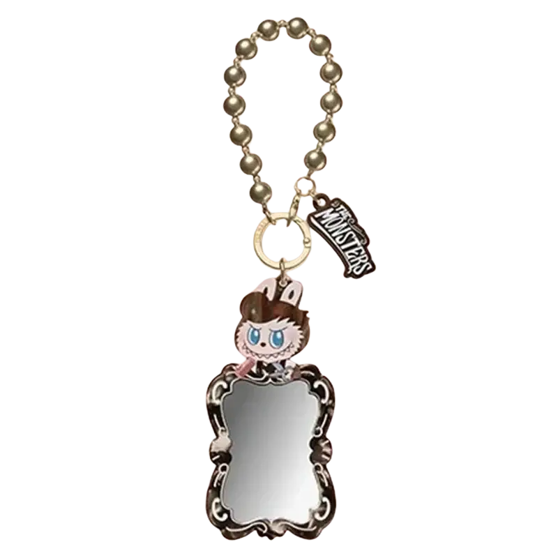 A silver-framed mirror charm with ornate detailing and a cartoon character from pop mart labuub guess bag