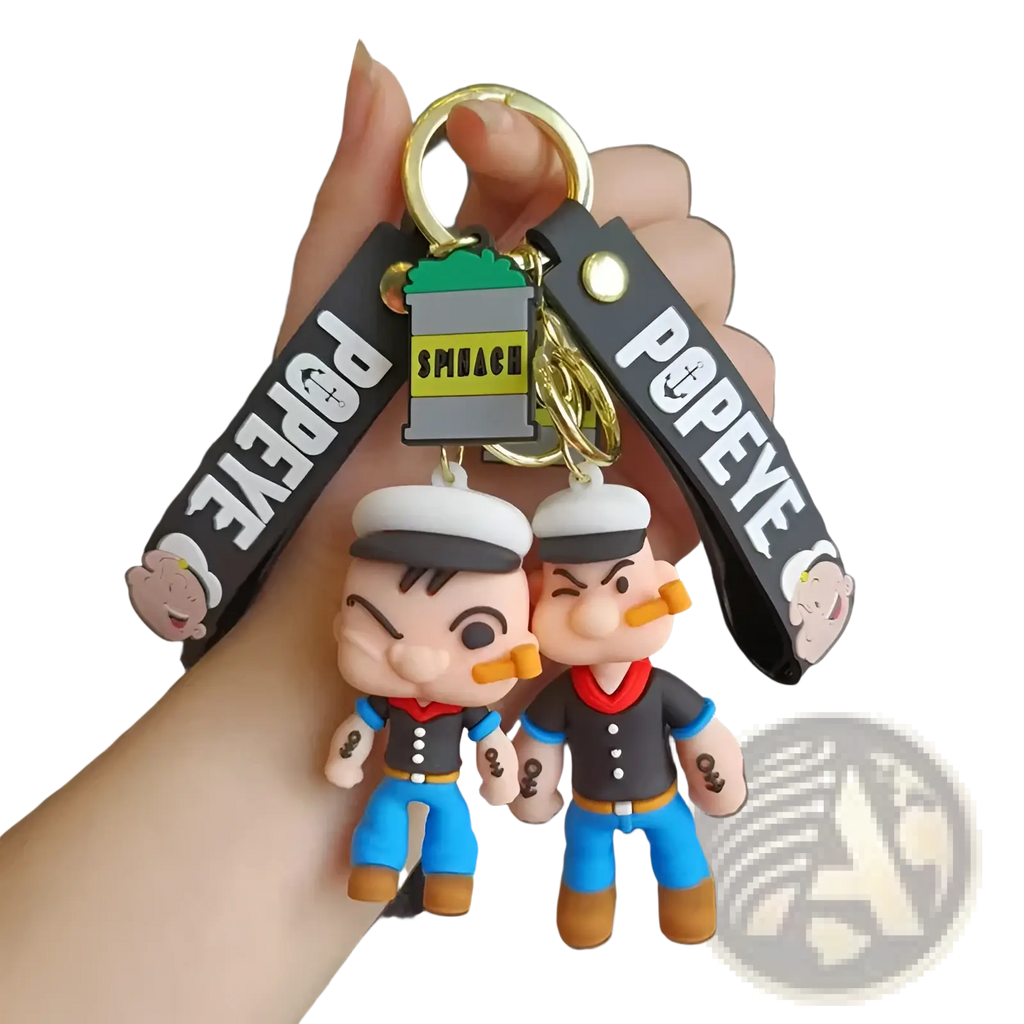 Popeye silicone keychain featuring two cartoon sailor figures in blue pants attached to gold ring and black strap with branding