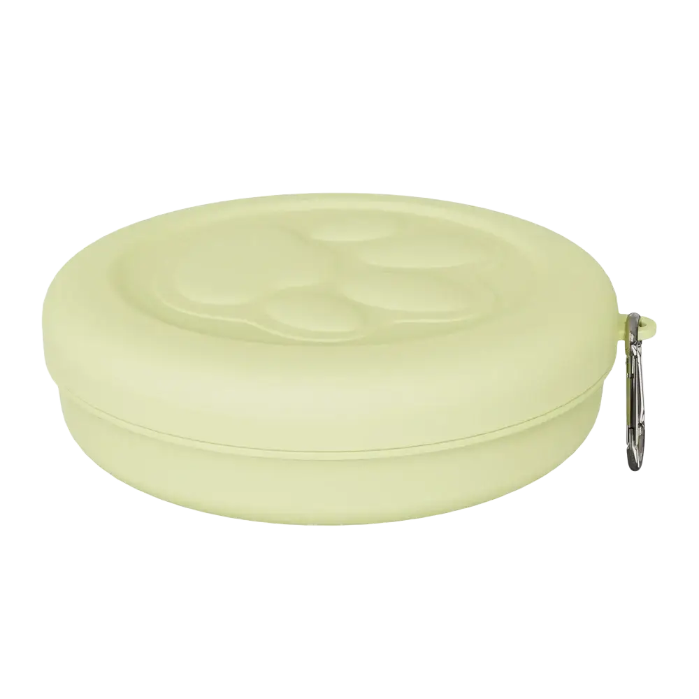 Portable dog travel bowl with treat storage in pale green silicone shaped like a paw print with silver carabiner clip