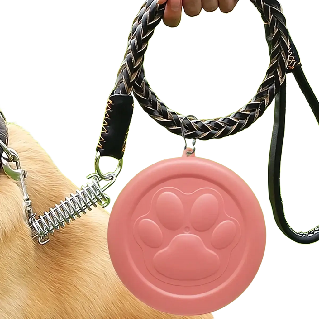 Portable dog travel bowl with treat storage featuring a pink silicone paw print leash clip and braided black and gray handle