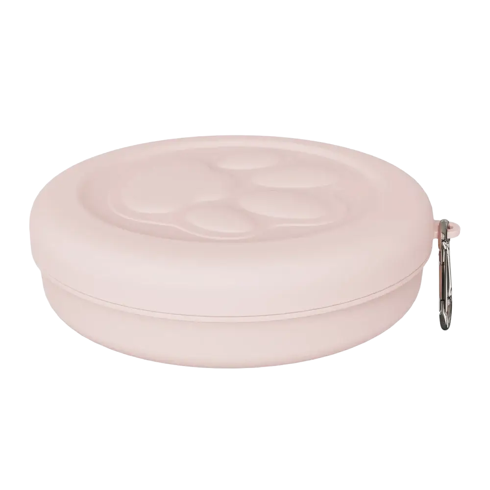 Portable dog travel bowl with treat storage in soft pink silicone featuring a molded paw print and silver carabiner clip