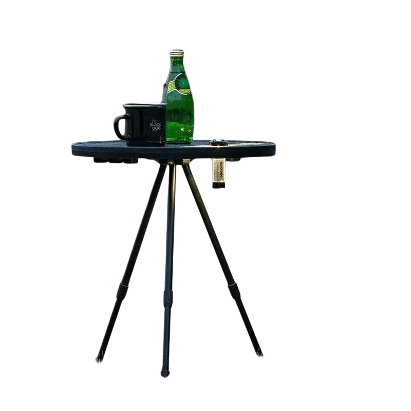 Black portable picnic camping table with round aluminum top and adjustable legs holding green bottle and black mug