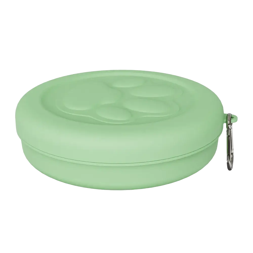 Portable travel dog bowl with treat compartment in soft mint green silicone featuring molded paw print and silver carabiner clip