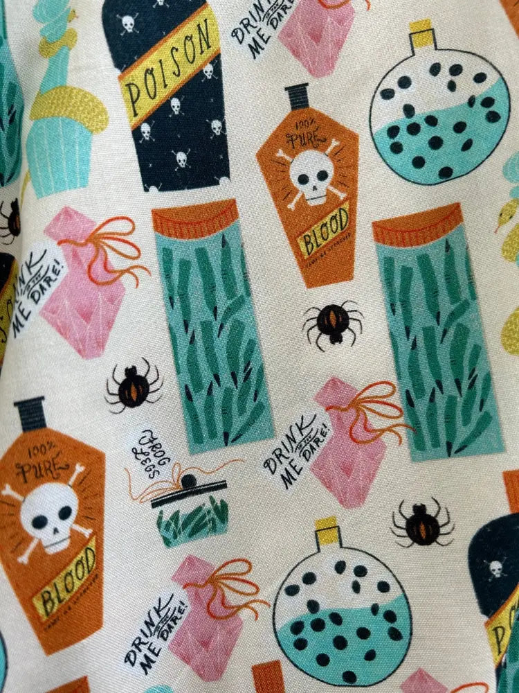 Potion skater skirt with whimsical halloween print featuring poison bottles potion vials and spiders on off-white fabric