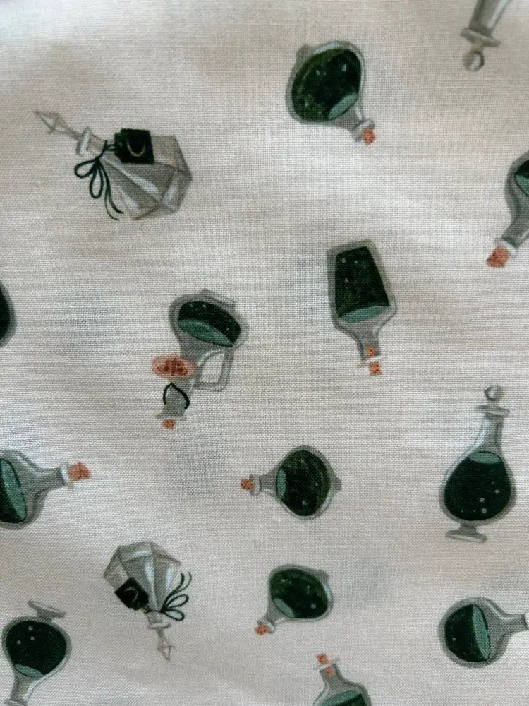 White fabric potions print vintage sleeveless bow top with side zipper featuring dark green and gray potion bottles with orange corks