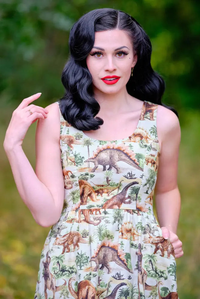 Sleeveless cream-colored cotton a-line dress with vintage prehistoric dinosaur print and tropical foliage detailing