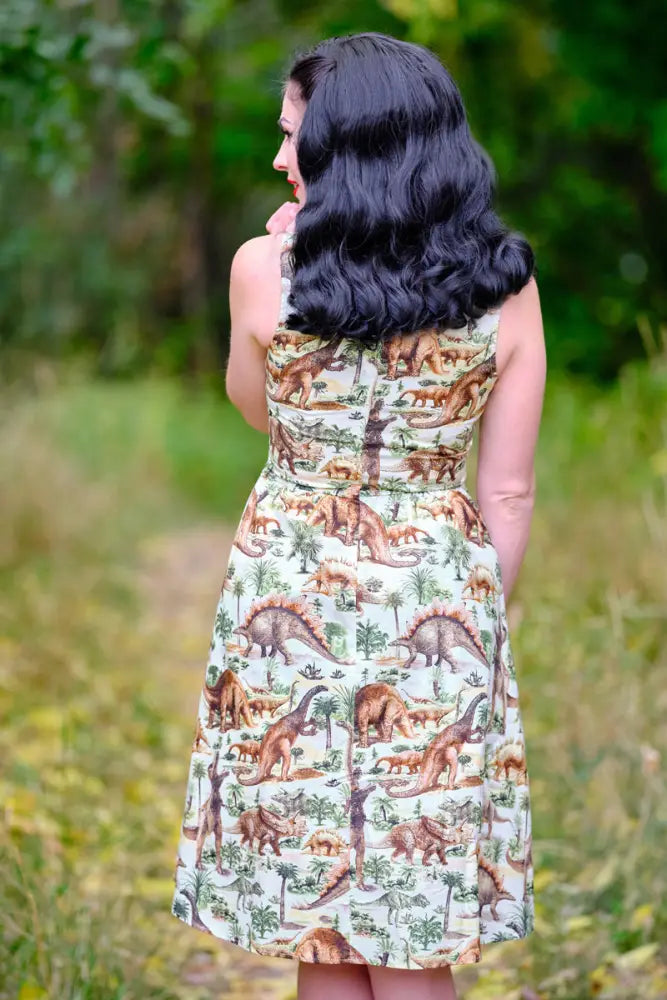 Vintage prehistoric dinosaur print sleeveless cotton a-line dress with detailed all-over dinosaur and tree print on cream background