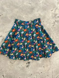 A vibrant prehistoric dinosaur floral print skater skirt with colorful patterns on a dark teal background