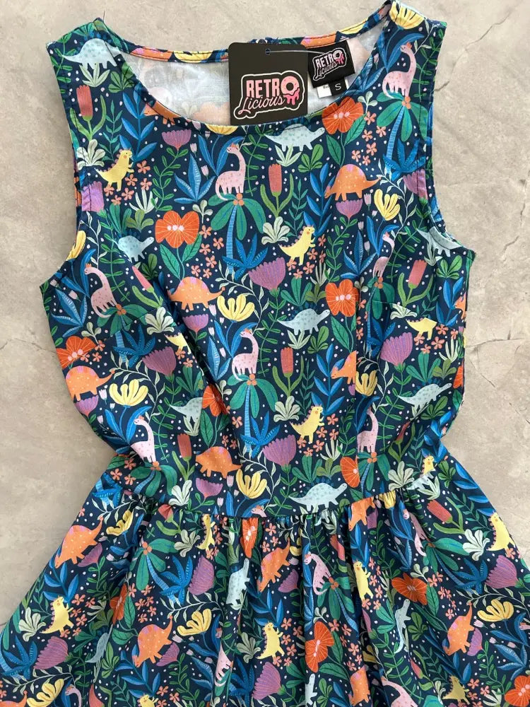 A vintage 1950s sleeveless dark blue cotton a-line dress with vibrant dinosaur and floral illustrations