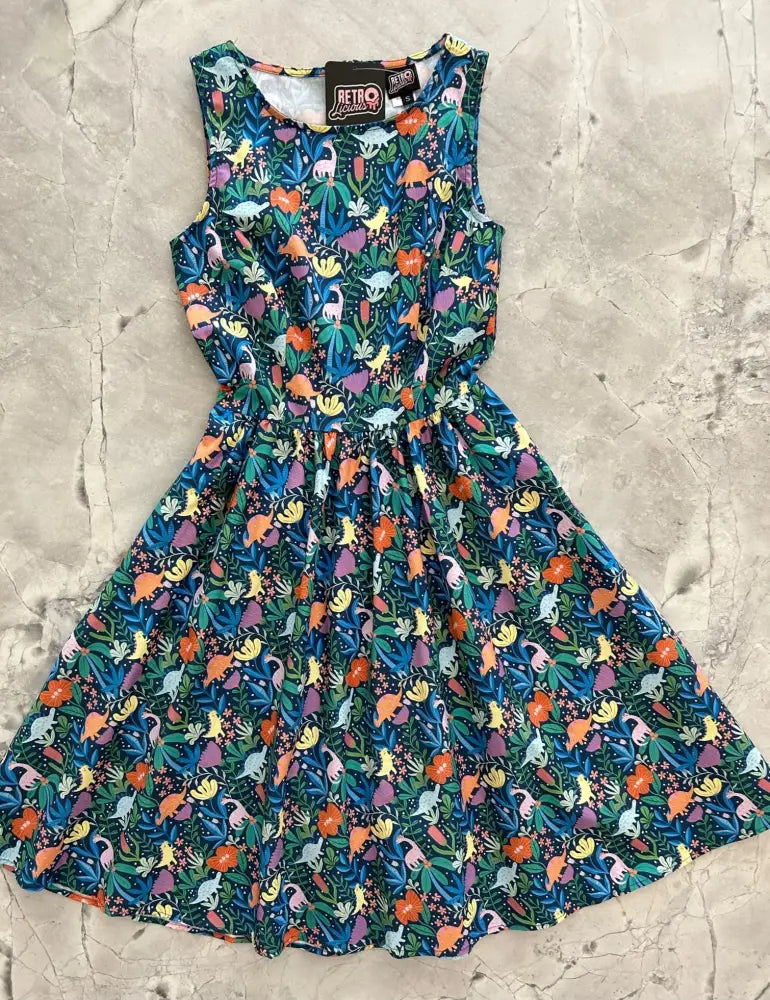 A vintage 1950s sleeveless cotton a-line dress in deep teal with colorful dinosaur and floral print