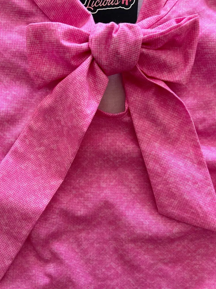A vibrant pink textured cotton top with a large bow at the neckline called retro pink mosaic cotton bow top