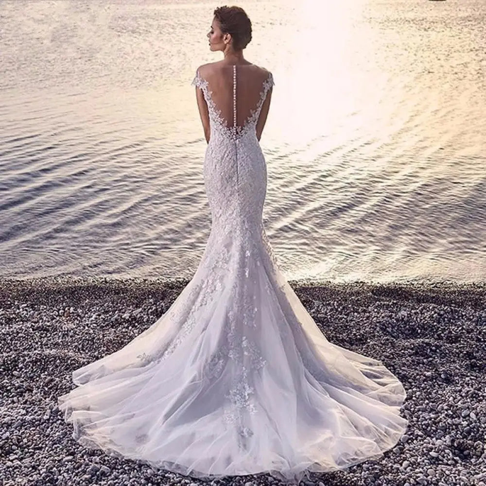 Back view of a white lace mermaid wedding dress with a beaded back and off-the-shoulder straps and train