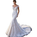 A white lace mermaid wedding dress with off-the-shoulder sleeves and a flowing train shown from the back side