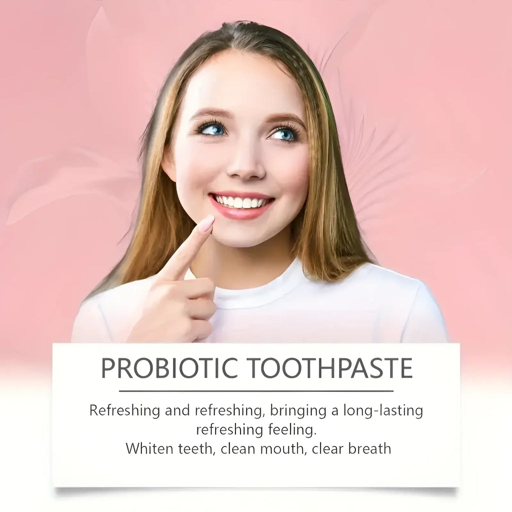 A woman with long brown hair and blue eyes smiles and points to her teeth promoting probiotic toothpaste for deep cleaning and fresh breath