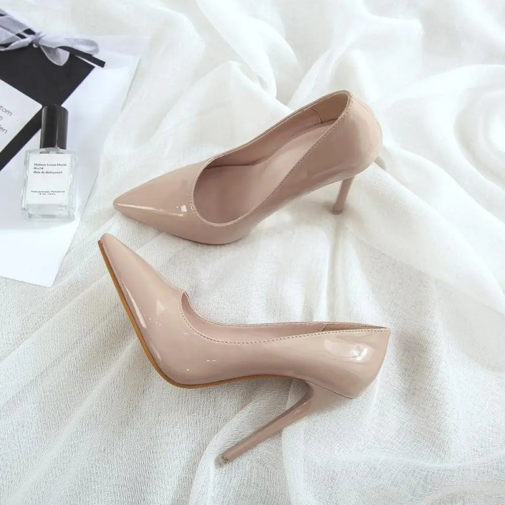 Pair of nude patent leather pointed toe stiletto pumps with slender high heels for elegant formal wear