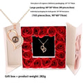 A projection heart necklace with a dark round pendant and sparkling crystals in a white gift box surrounded by roses