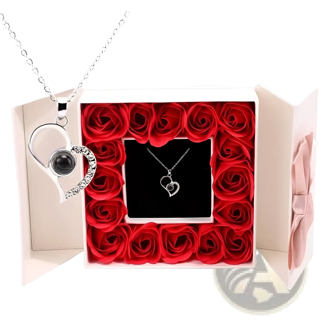 Silver heart-shaped projection necklace with black gemstone and rhinestones in gift box surrounded by red roses