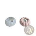 A matte pink and a white pumpkin candle holder silicone mold with a central wax candle for decorative use