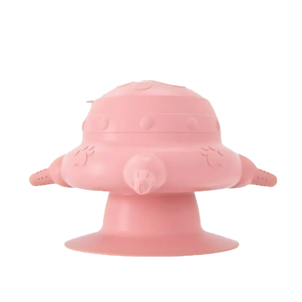 Pink silicone puppy milk feeder shaped like a rounded spaceship with wing-like appendages and a central nozzle