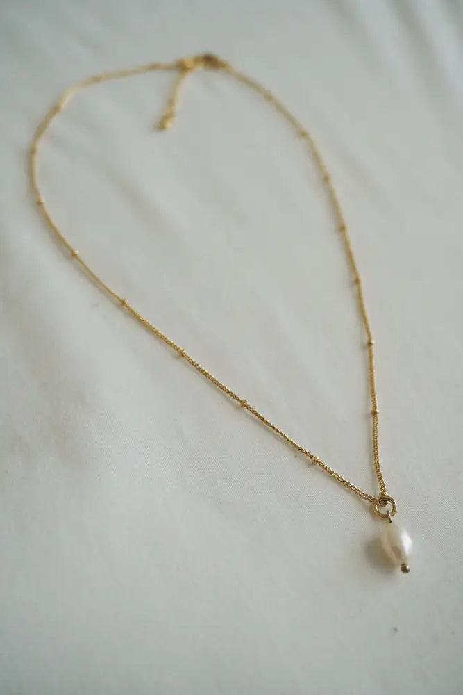 A delicate gold chain necklace with a single white pearl pendant from the Pure Pearl and Gold Bead Layered Necklace Set