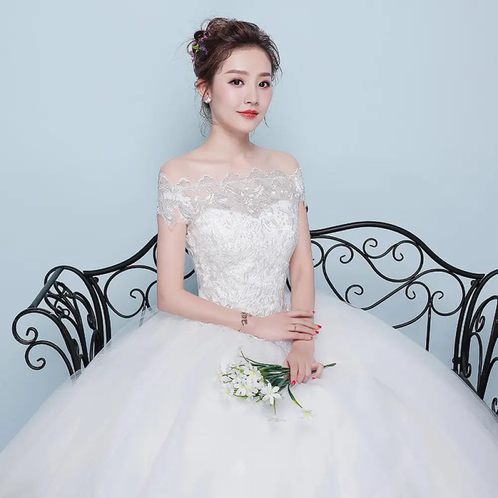 A white qidi lace off the shoulder tulle ball gown wedding dress with intricate lace detailing and a voluminous skirt