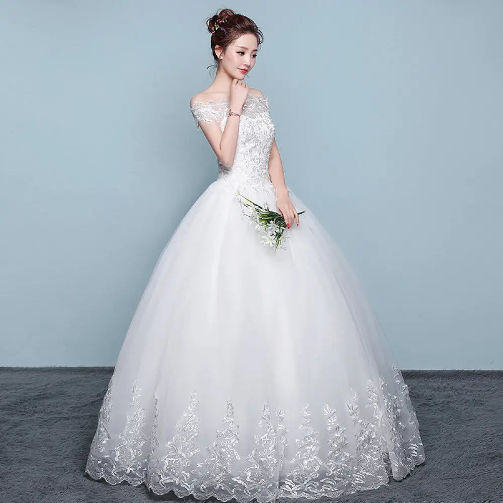 A white off the shoulder wedding gown featuring intricate Qidi lace detailing and a voluminous tulle ball gown skirt