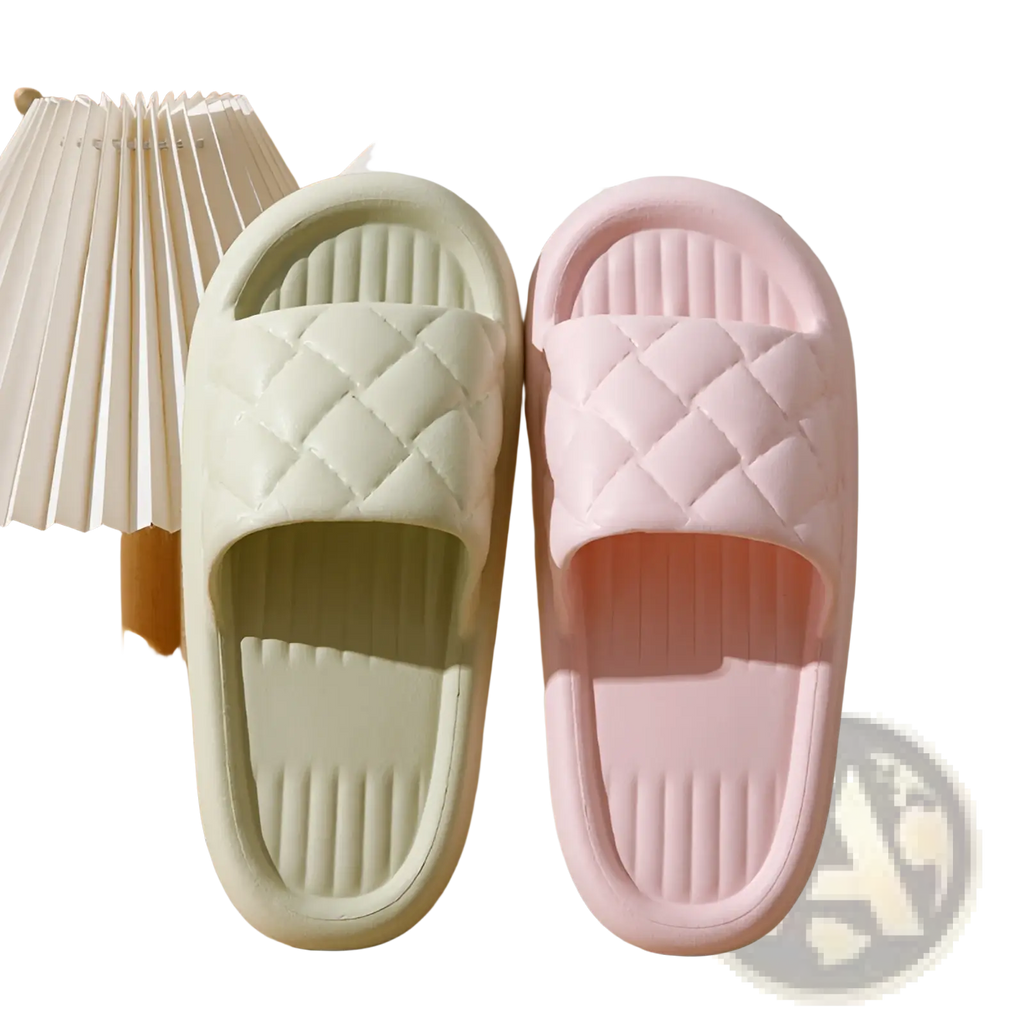 A pair of pastel-colored quilted non slip lightweight rubber slide sandals in soft mint and blush pink for home use