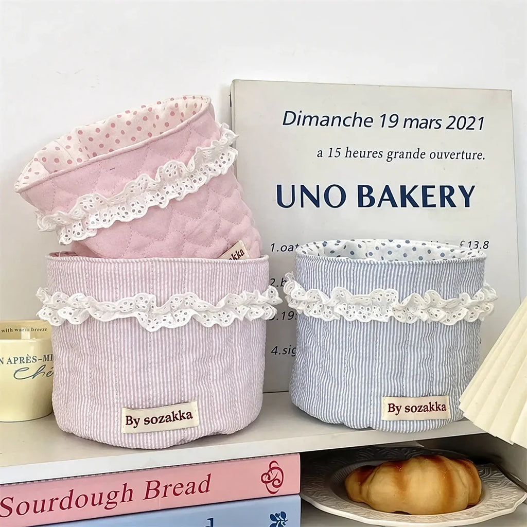 Quilted nursery storage baskets with pink and blue striped fabric and white lace trim for organized storage