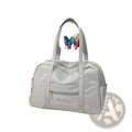 Light gray quilted nylon travel tote bag with structured dual handles and multiple zippered compartments with plush charm