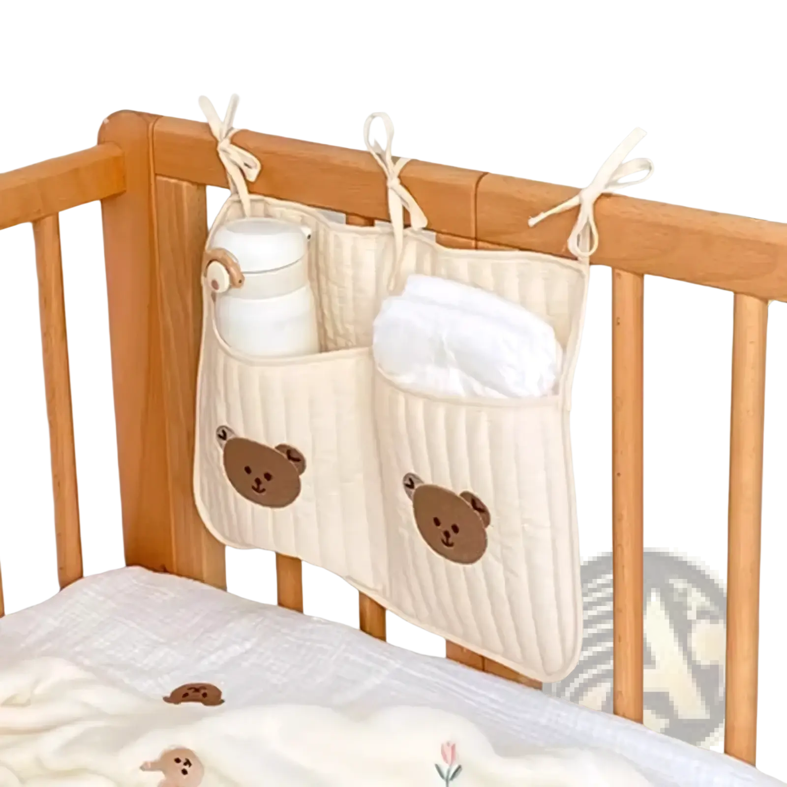 Cream-colored quilted stroller organizer bag with bear embroidery and three tied ribbon loops for hanging on crib sides