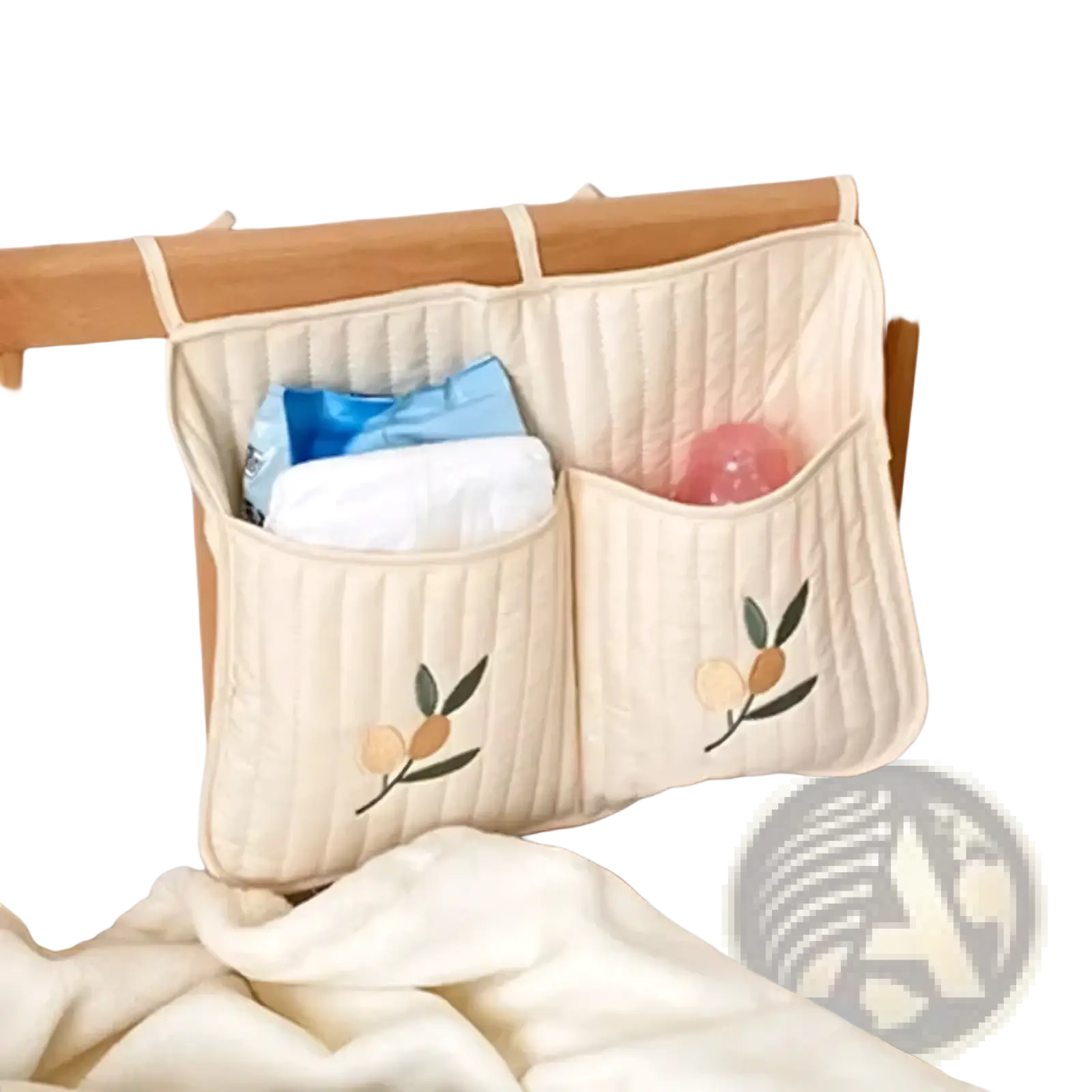 Cream-colored quilted stroller organizer bag with bear and embroidered fruit motifs hanging on wooden crib rail