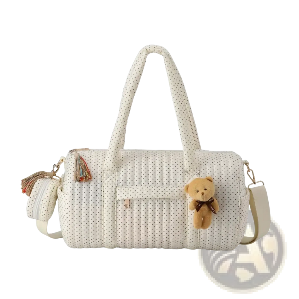 Cream-colored quilted stroller organizer bag with black polka dots featuring plush teddy bear charm and tassel accents