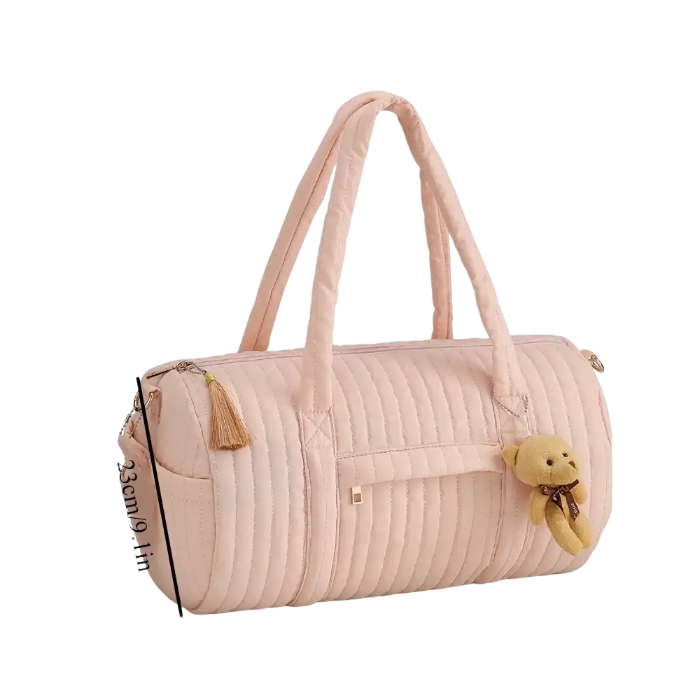 A soft pink quilted stroller organizer bag with plush teddy bear charm and tassel accents in fabric material