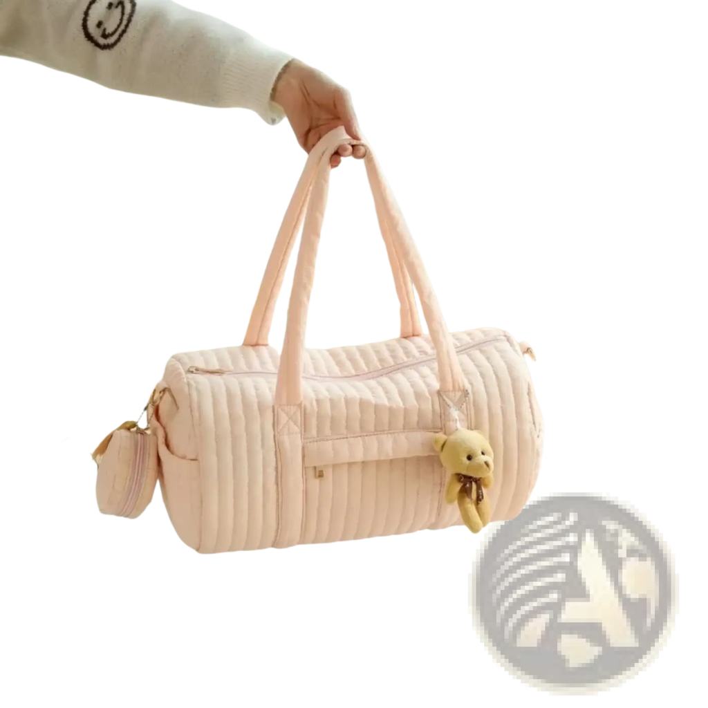 A soft pink quilted stroller organizer bag with long handles and a small teddy bear charm on the side