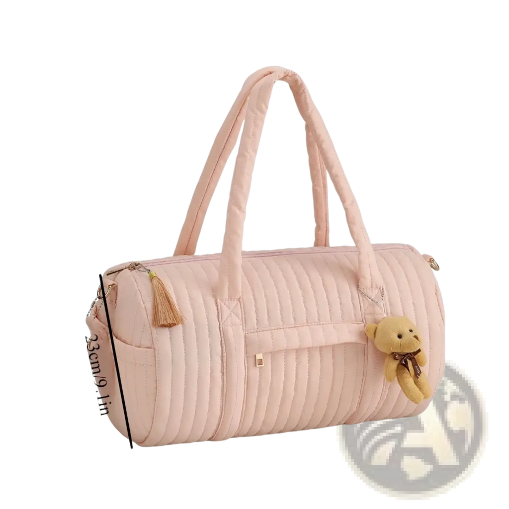 A soft pink quilted stroller organizer bag with plush teddy bear charm and tassel accents in fabric material