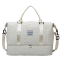 Cream-colored quilted large travel duffel bag with silver-toned hardware and front patch label for weekender use