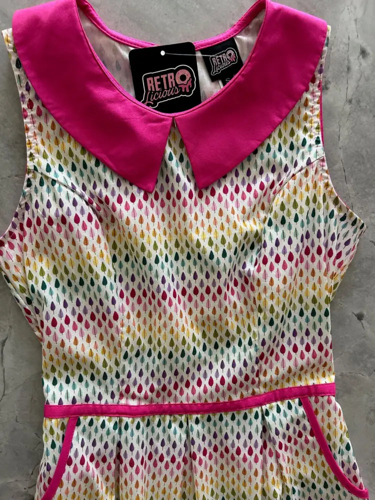 A vibrant retro style sleeveless cotton dress with a pink satin peter pan collar and rainbow teardrop pattern