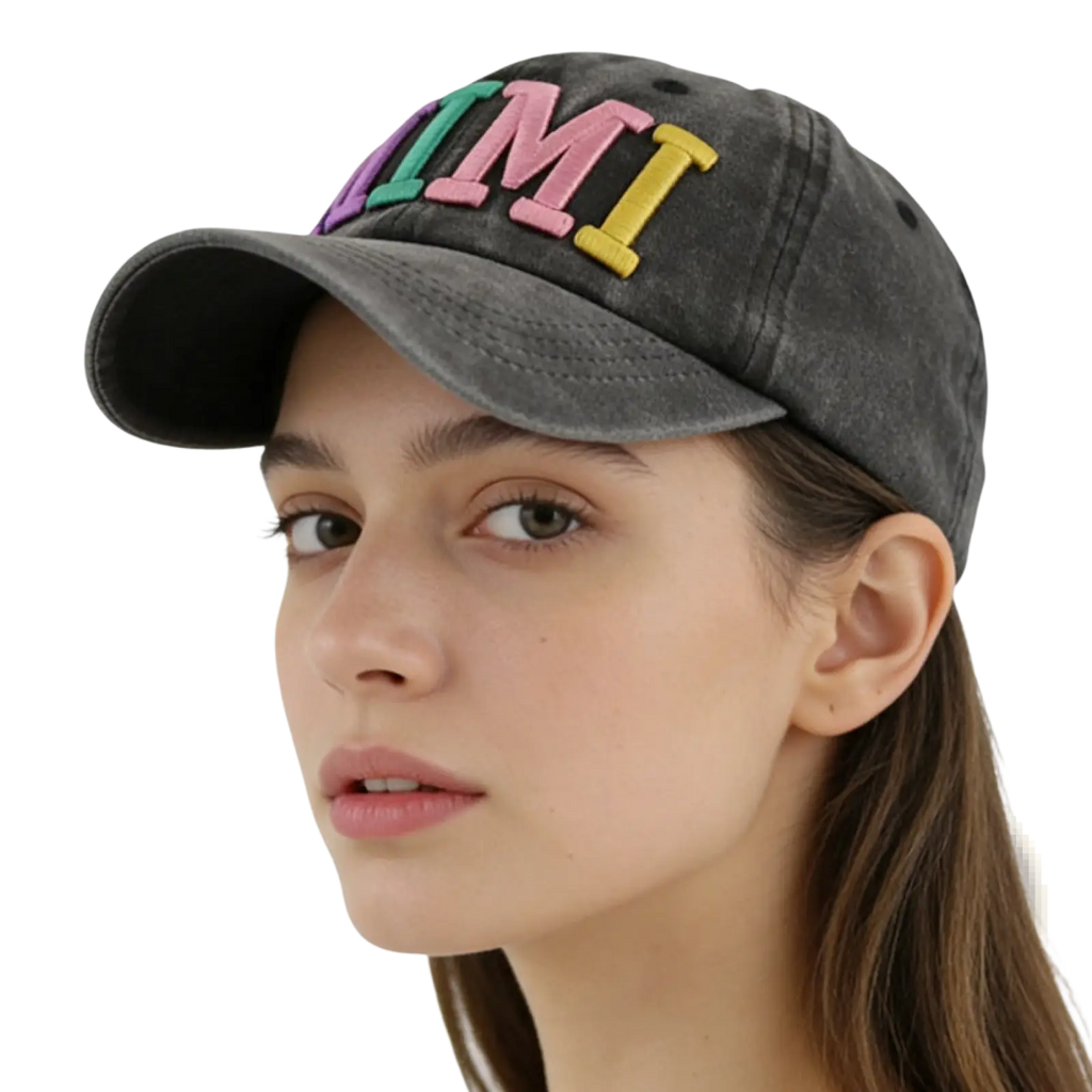 A faded black baseball cap with colorful embroidered letters spelling mimi in pink green and yellow
