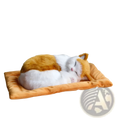 A realistic breathing plush calico cat figurine with white and orange fur resting on a golden-orange cushion pet bed