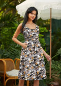 A sleeveless midi dress with pockets featuring a playful black white and tan cat print on dark gray fabric