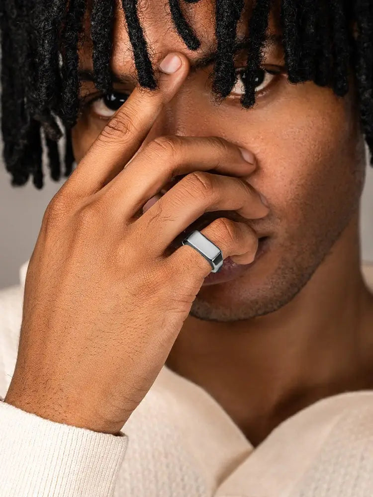 A polished silver rectangle stainless steel signet ring with a sleek minimalist design worn on a model’s finger