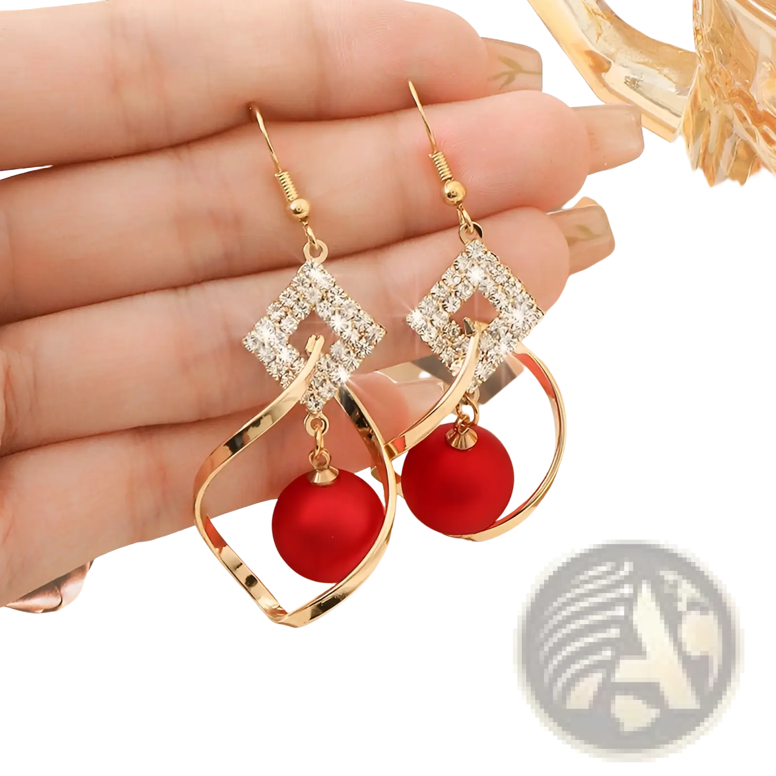Gold dangle earrings with diamond-encrusted square tops and vibrant red bead pendants in a geometric design