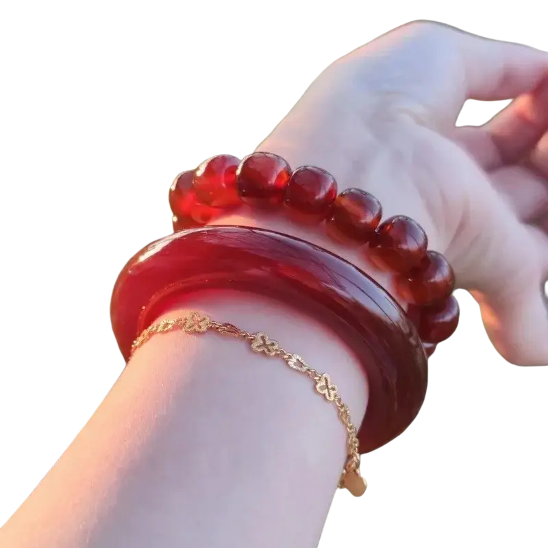 A glossy deep red jade bangle bracelet for women worn on a wrist in classic round style