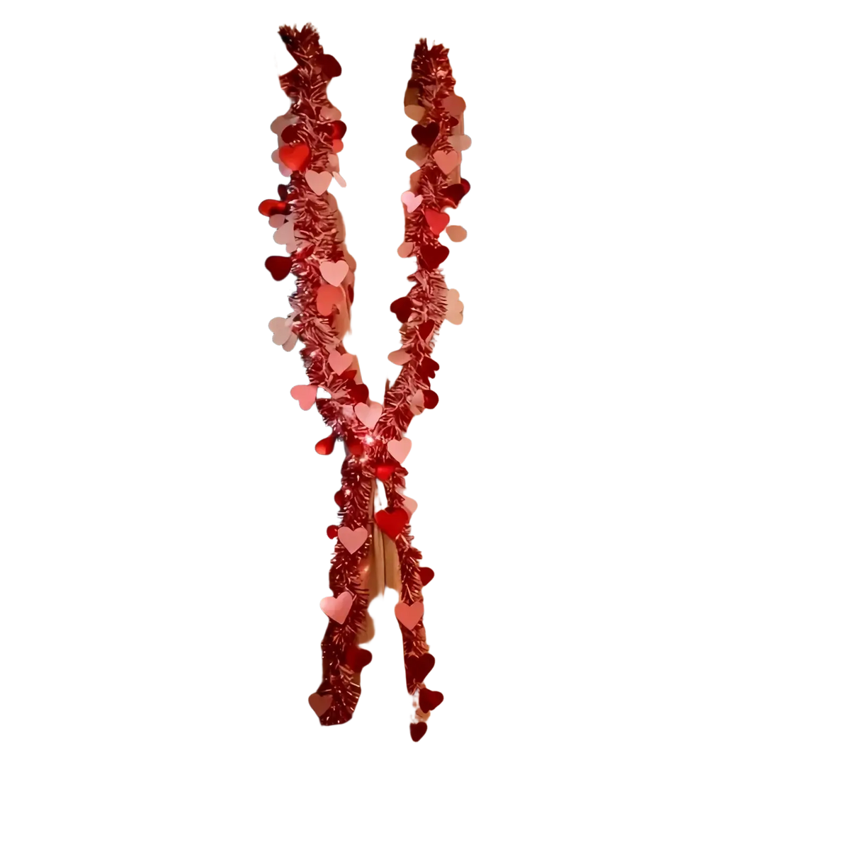A red and pink metallic heart tinsel garland with festive heart decorations draped on window curtains for Valentine decor