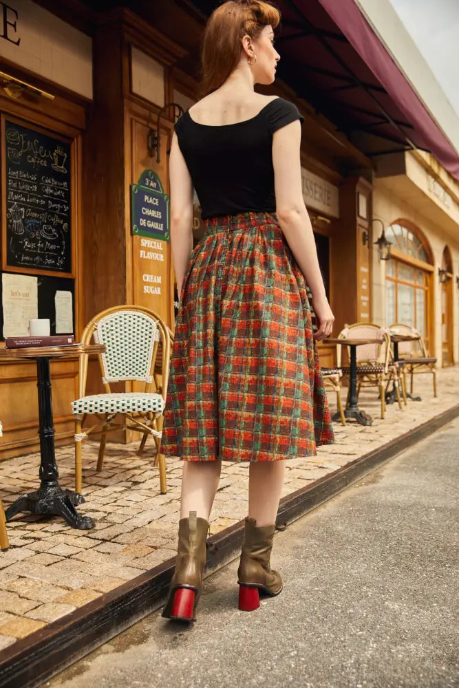 A woman wears a vintage-style holiday plaid doris high waisted cotton flare skirt with bold red green and beige plaid pattern