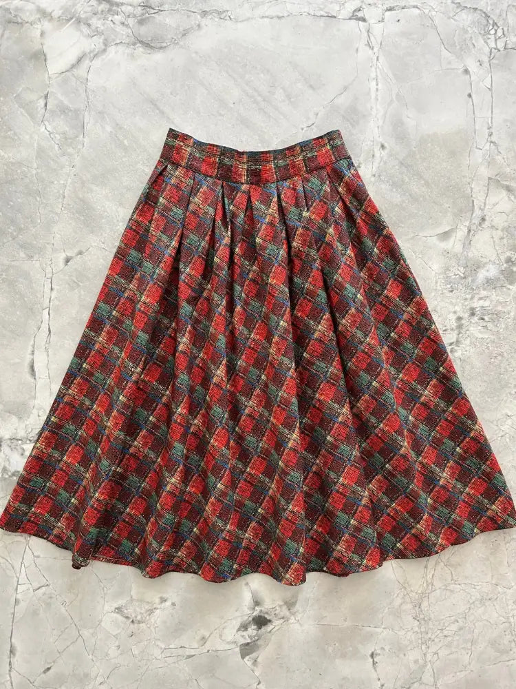 A flared high waisted skirt with red green and black plaid pattern made of textured woolen fabric with pockets