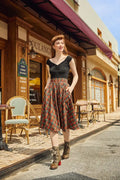 A woman wearing a holiday plaid Doris high waisted cotton flare skirt with pockets in red and green paired with a black sleeveless top